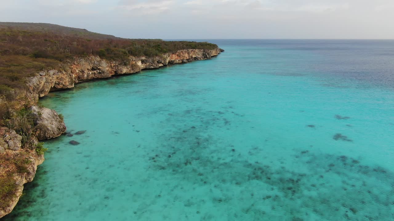 Spiaggia di Kokomo delimitata da scogliere a Curaçao con acque turchesi.