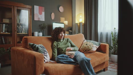 young asian girl eating popcorn and watching tv at home