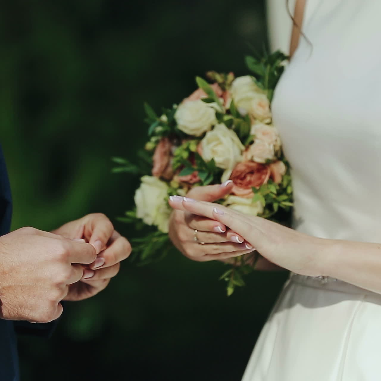 Newlyweds exchange rings at the wedding ceremony over green grass background. Wedding rings. Square video