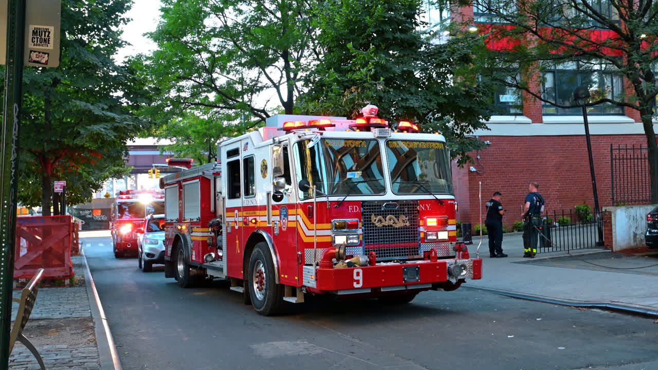 New York, ABD, 2 Ağustos 2025: Şehir caddesinde yanıp sönen ışıklarla kırmızı FDNY itfaiye aracı. New York, Chinatown'da tuğla bina arka planıyla acil duruma müdahale eden bir itfaiye aracının ön görünümü.