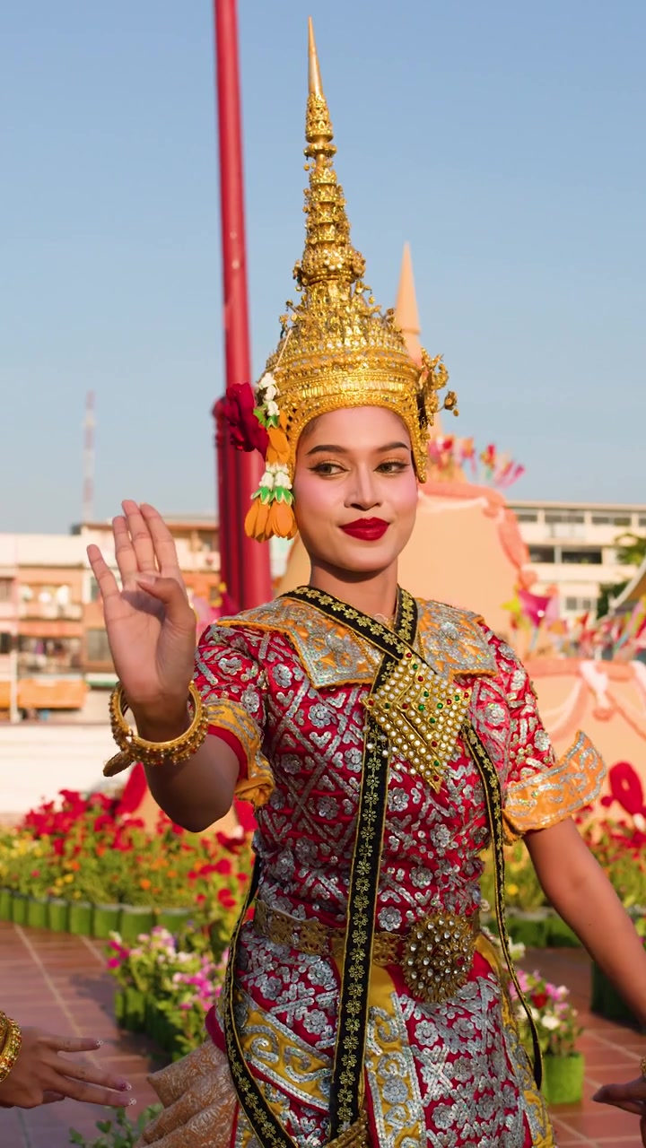 Uma dançarina em traje clássico ornamentado executa movimentos tradicionais de Khon em um templo
