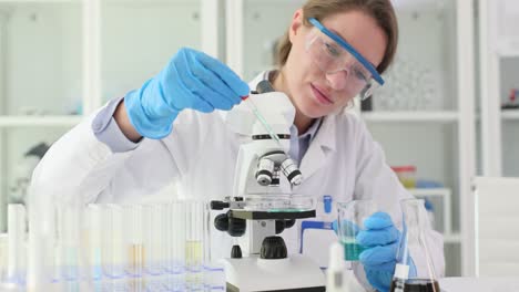 female scientist working with microscope and chemicals in lab