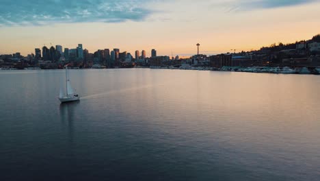 disparo de seguimiento aéreo de un velero en el lago union y la hermosa silueta del horizonte de la ciudad de seattle en el fondo