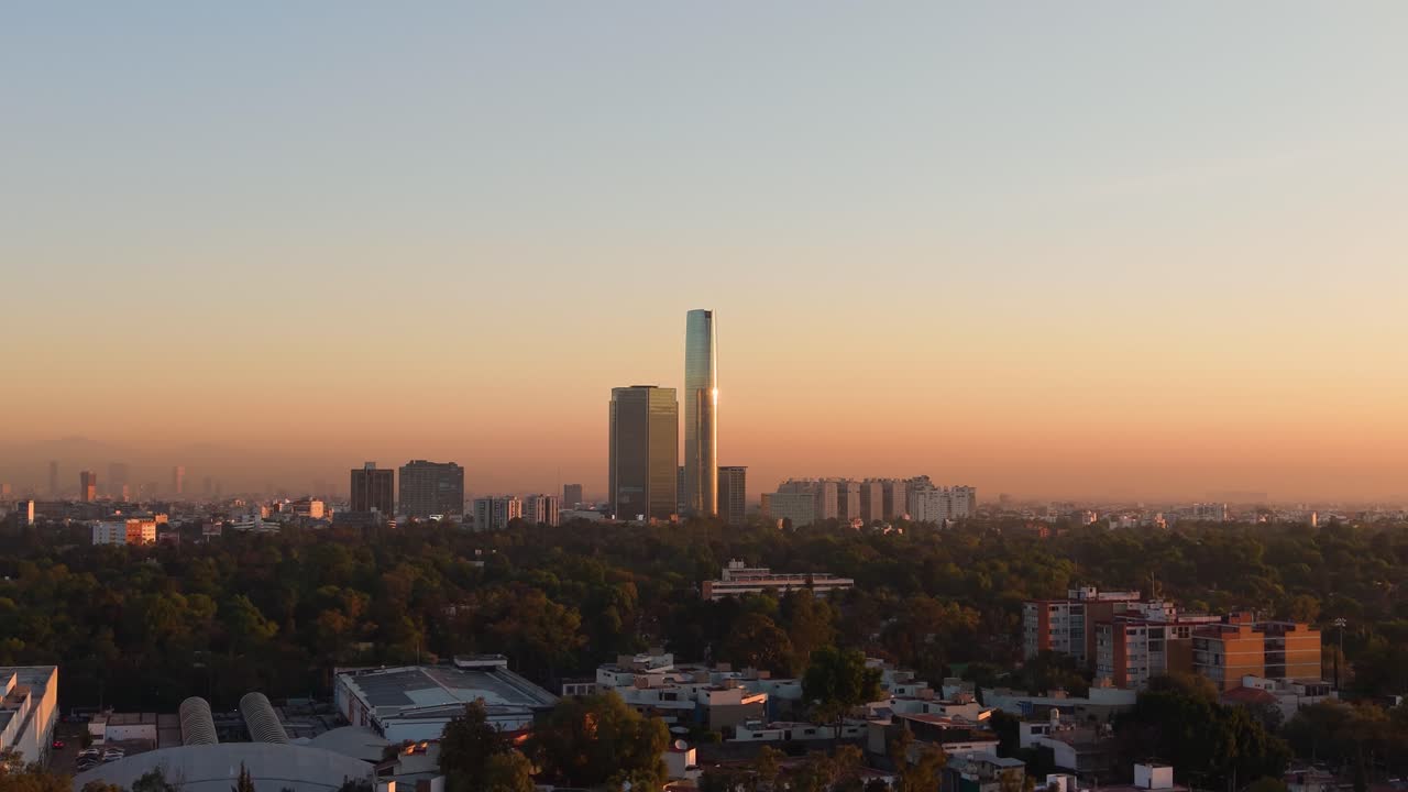 Skyline della zona sud di Città del Messico con la torre più alta che riflette l'alba, ripresa con drone.