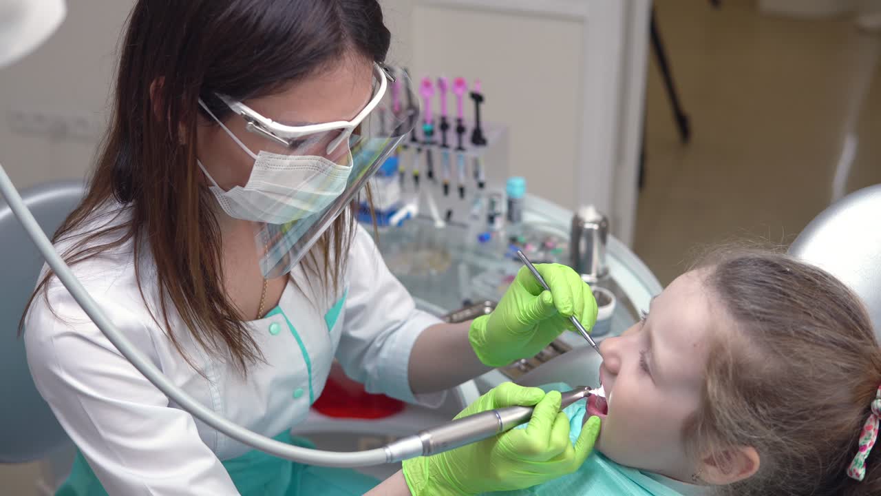 Dentist cleans girl's teeth with professional toothpaste. Girl with white teeth at the dentist's office. Shot in 4k