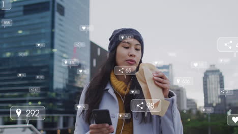 Animation-of-social-media-icons-over-biracial-woman-having-a-snack-whle-walking-outdoors