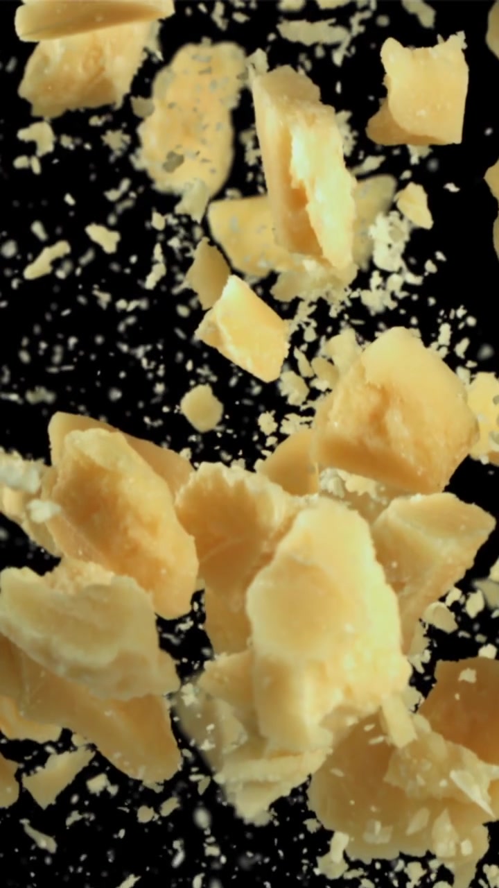 Parmesan Cheese Pieces Falling in Slow Motion on Black Background