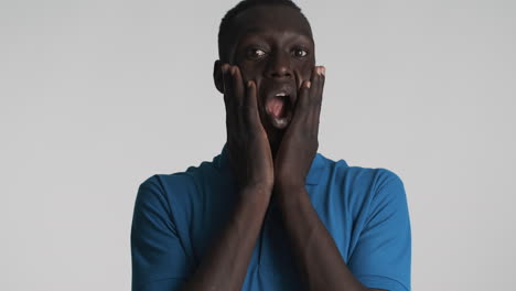 sorprendido hombre afroamericano en fondo gris.