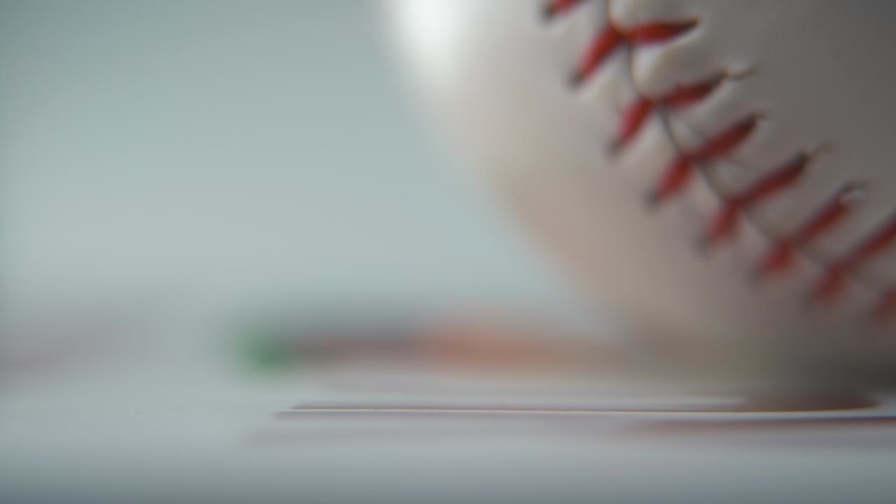Cinematic commercial zoomed in macro shot of a rolling white base ball, close-up on red stitches, baseball roll, professional studio lighting, smooth slow motion 120 fps close-up