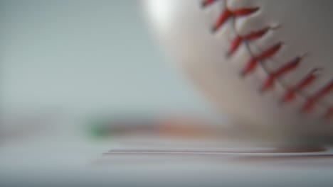 comercial cinematográfico ampliado en macro toma de una pelota de base blanca rodando, primer plano en puntos rojos, rollo de béisbol, iluminación de estudio profesional, movimiento lento suave 120 fps primer plano