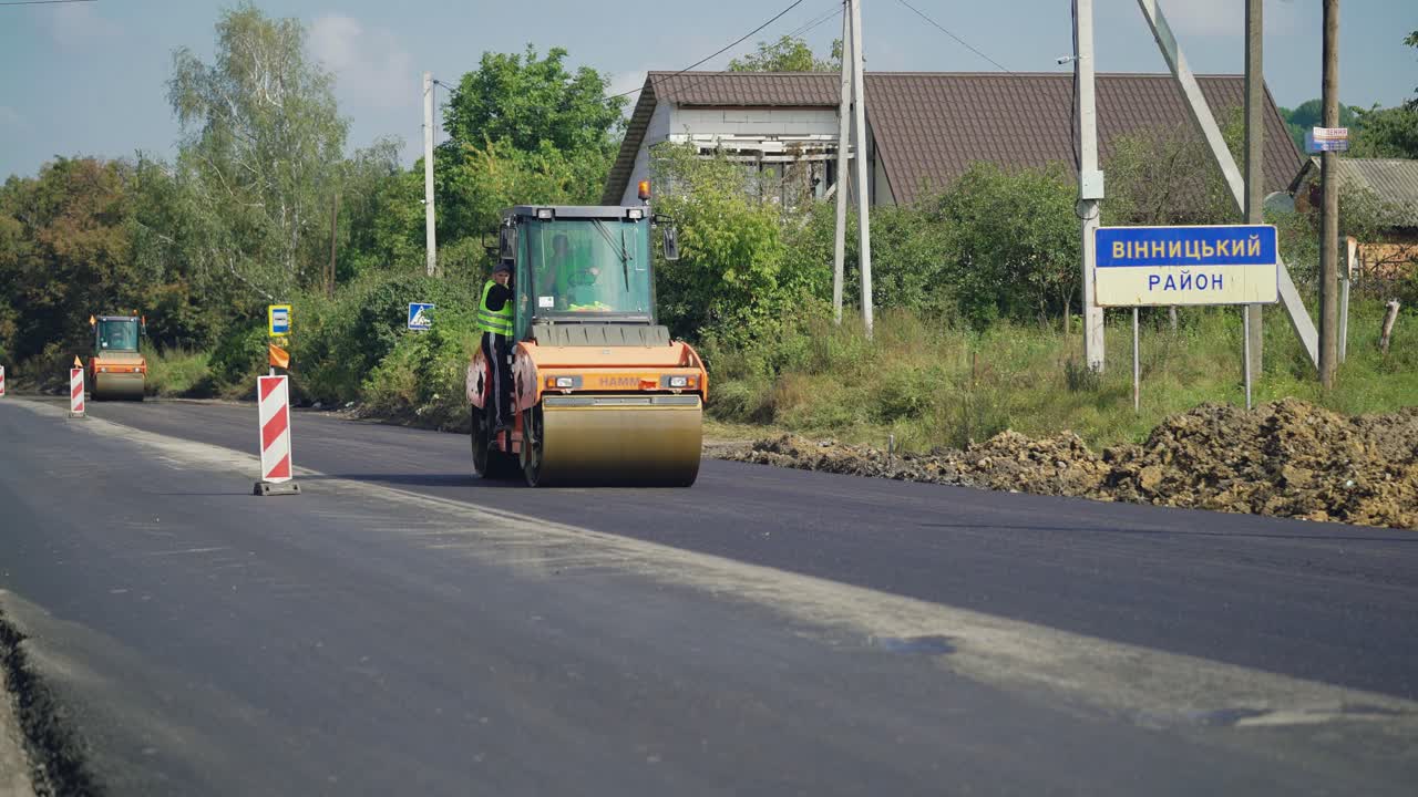 a steamroller rides through the new asphalt to level the surface. Close-up