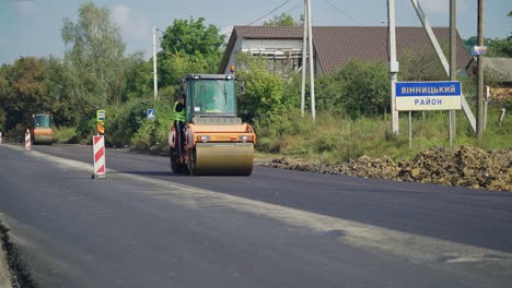 a steamroller rides through the new asphalt to level the surface. close-up