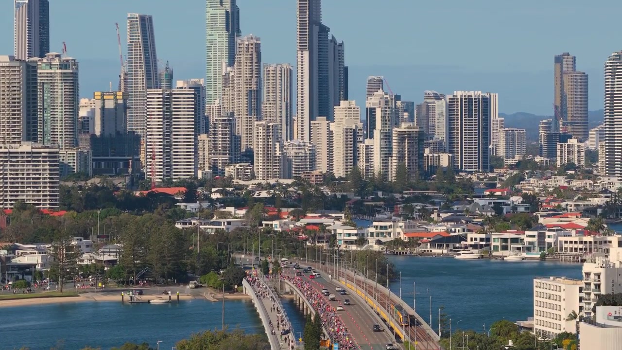 Filmato aereo orizzontale con panoramica a sinistra, poi innalzamento con una lenta inclinazione verso il basso sopra il ponte Sundale, Southport e la Maratona della Gold Coast, Gold Coast, Queensland, Australia
