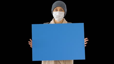 mujer con ropa de exterior y máscara médica con una tabla en blanco,