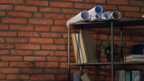 joven arquitecto o diseñador árabe tomando su proyecto de dibujo, abriéndolo sobre la mesa y comenzando a trabajar sobre él