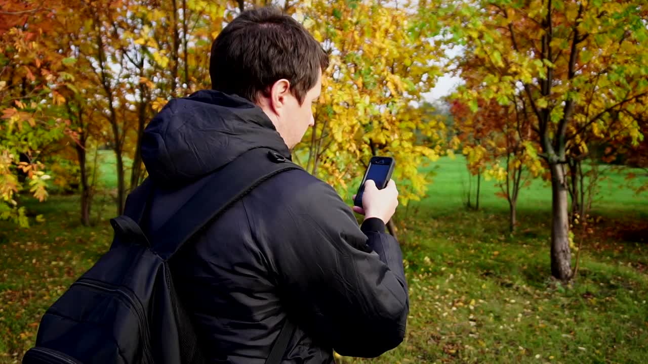 Man using a phone in an autumn park