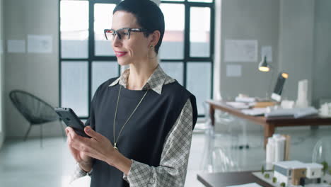 mujer de negocios de mediana edad que usa un teléfono inteligente en la oficina