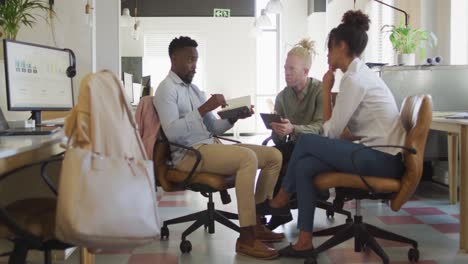 happy diverse business people discussing with documents in creative office