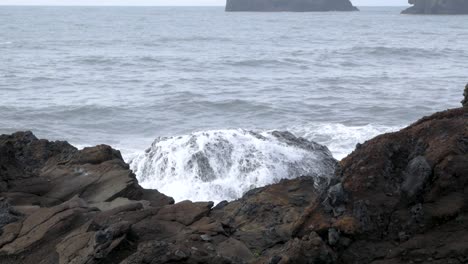 slow motion waves crashing over a volcanic boulder