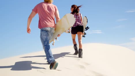 hombre y mujer caminando con tablas de arena en los desiertos 4k