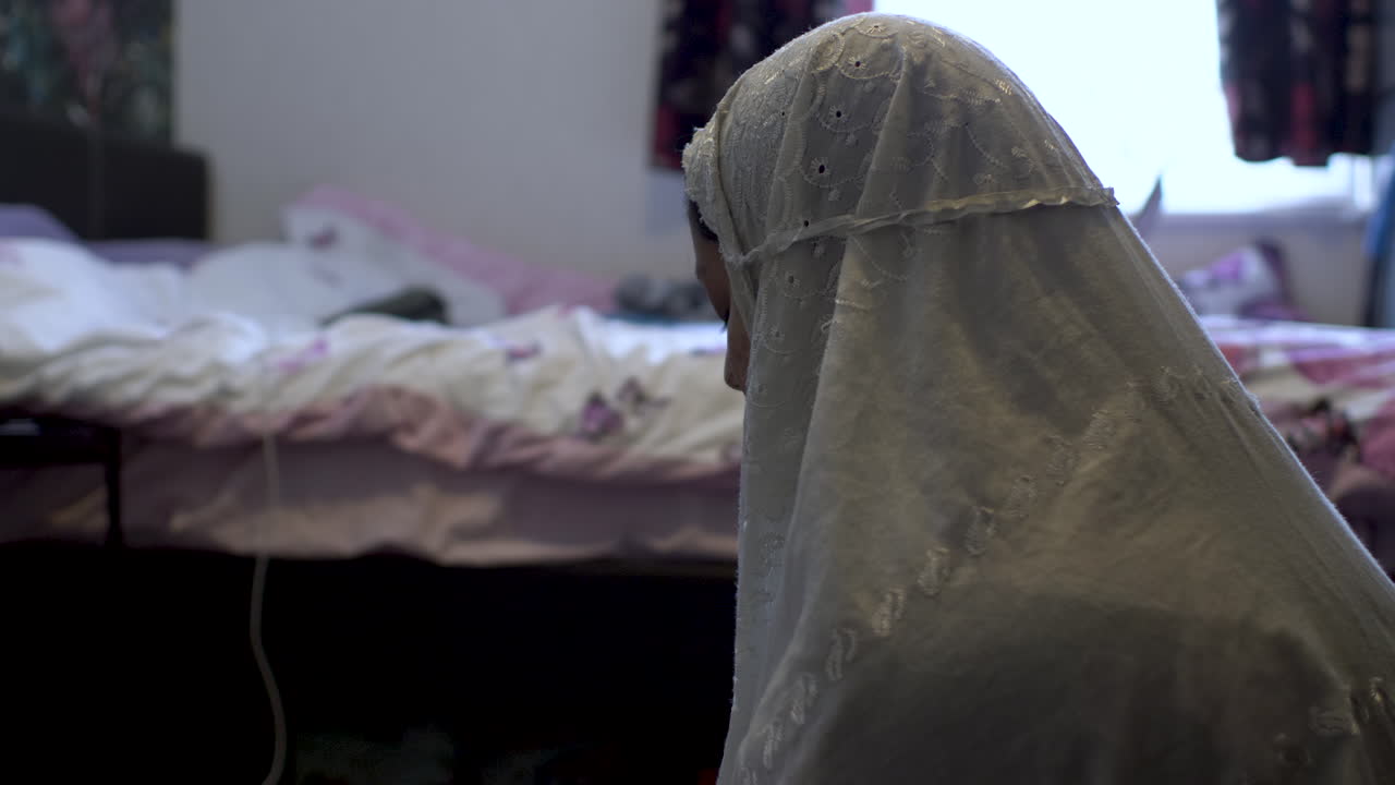 Young Muslim Female Wearing White Hijab Praying In Bedroom