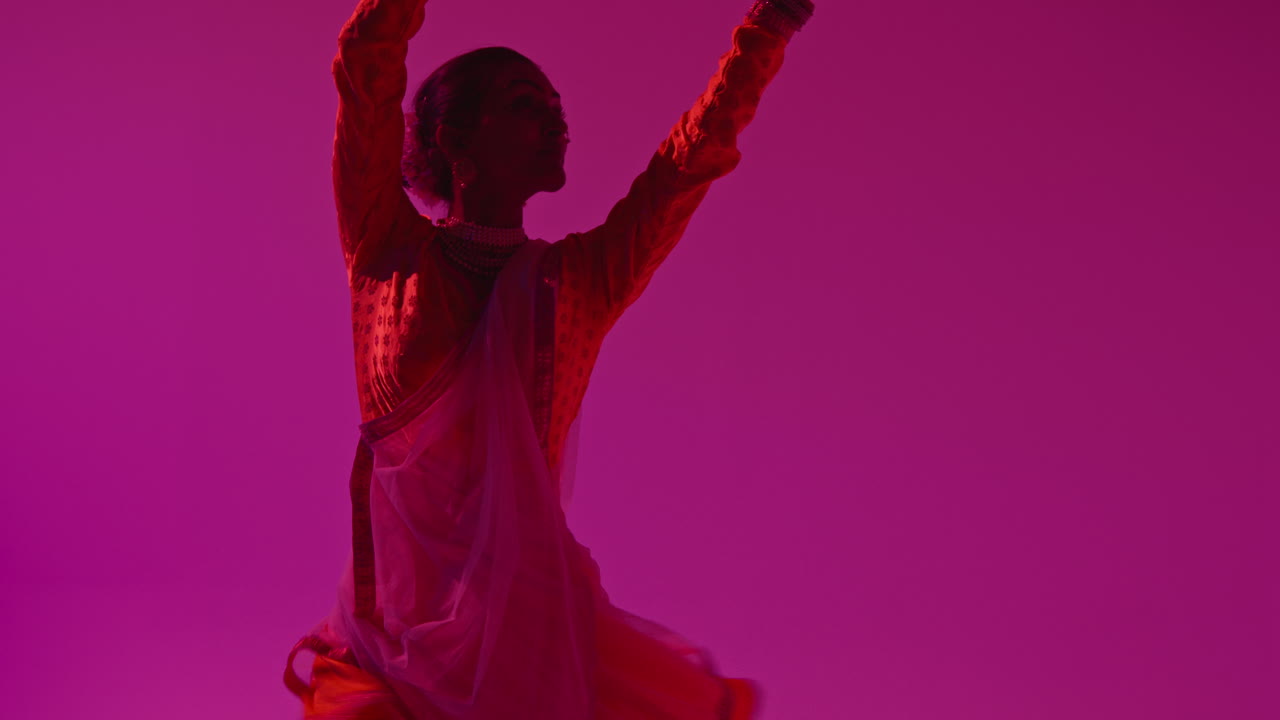 bailarina de kathak giratoria que realiza una danza vestida con el vestido tradicional indio contra un fondo púrpura 4