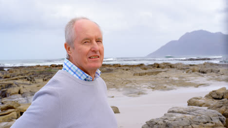 front view of old caucasian senior man standing at beach 4k