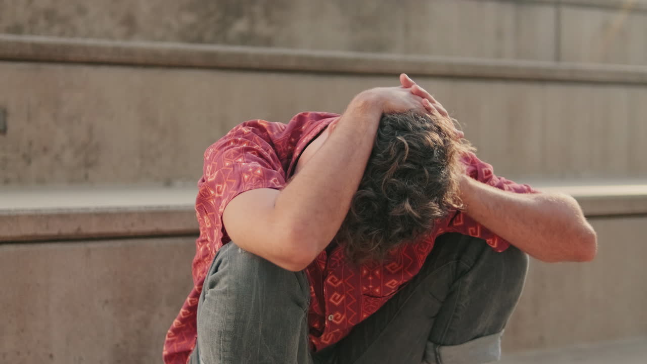 Un uomo seduto sulle scale in preda all’angoscia