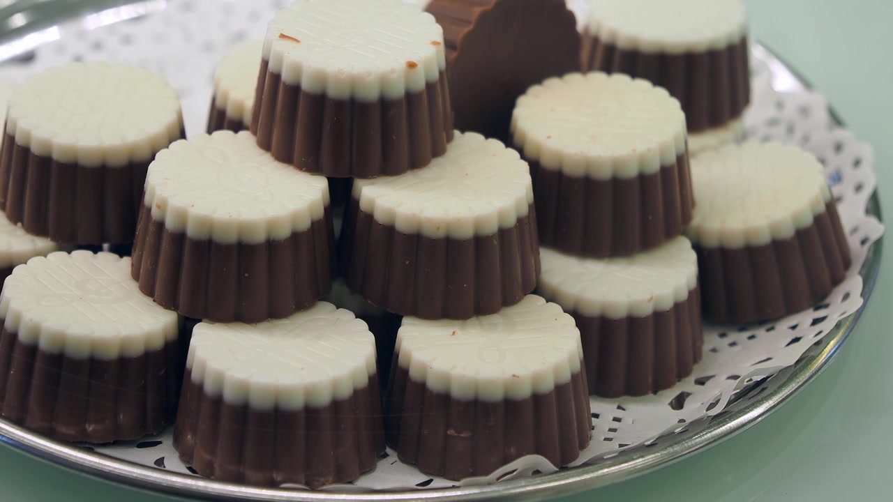 Pila di praline al cioccolato bicolore gourmet su un vassoio d'argento.