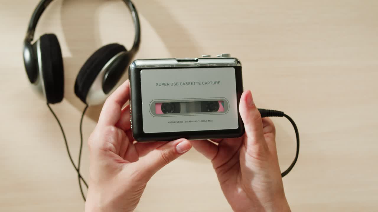 manos sosteniendo un reproductor de casetes vintage y auriculares
