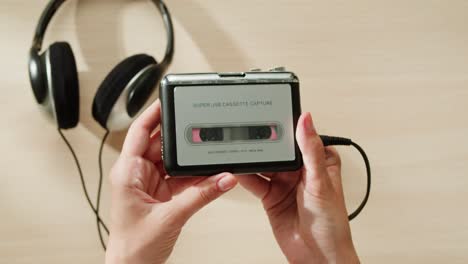 hands holding a vintage cassette player and headphones