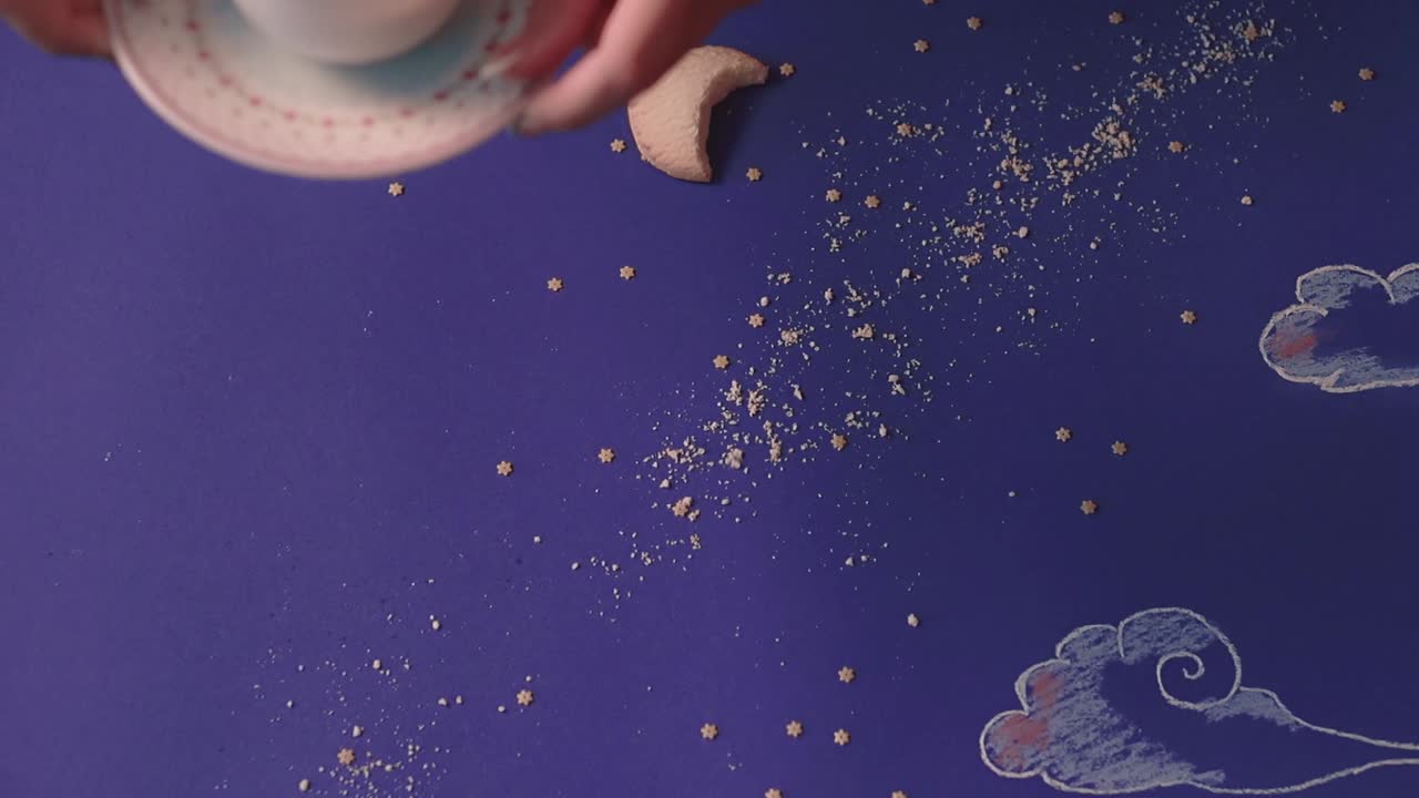 кто-то берет с стола, сделанного в виде ночного неба, кружку кофе вблизи