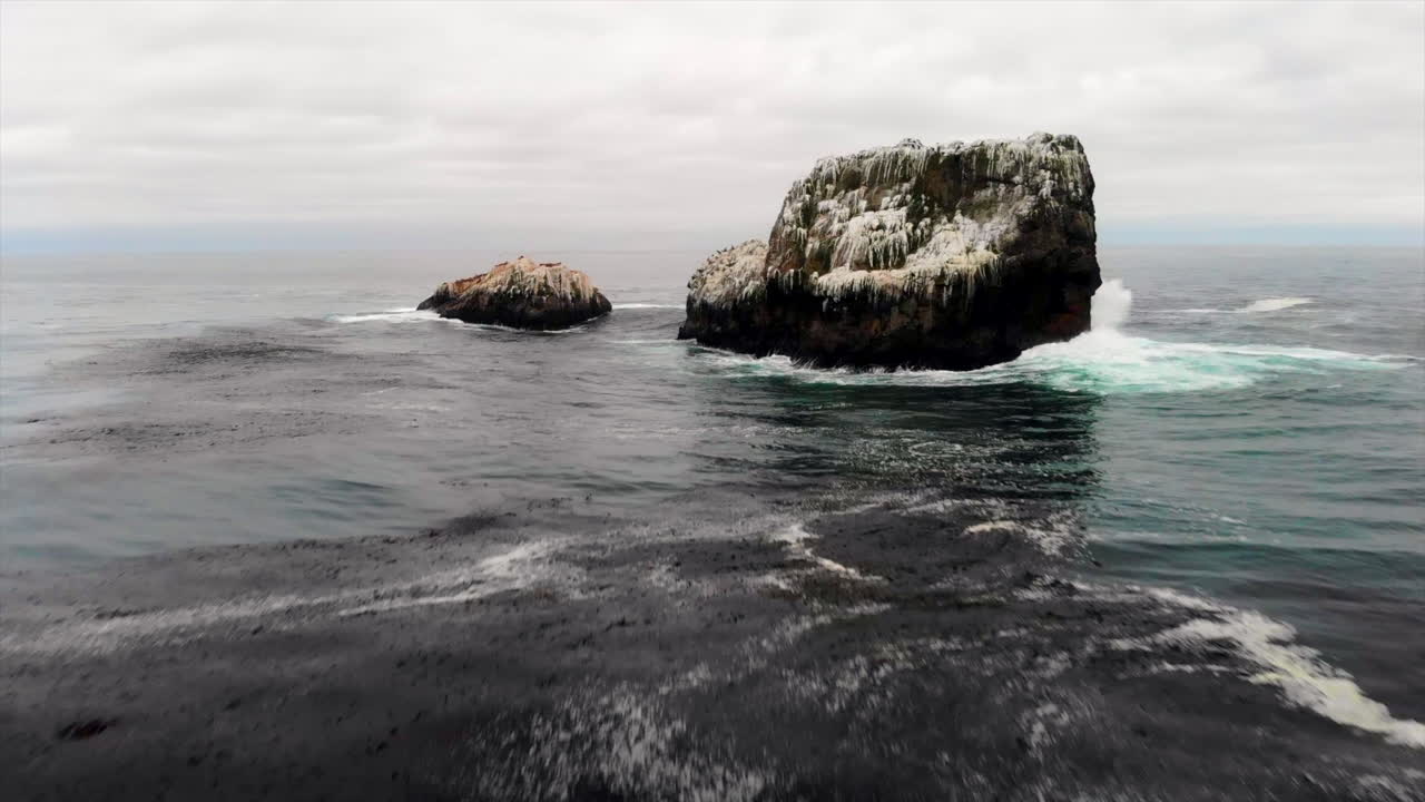 drone vuela arriba y arriba cubierto de guano blanco aves rookery roca monolítica en el océano pacífico frente a la costa central de california con olas estrelladas, a lo largo de la autopista 1, big sur, san simeon, 4k pro res 422 hq