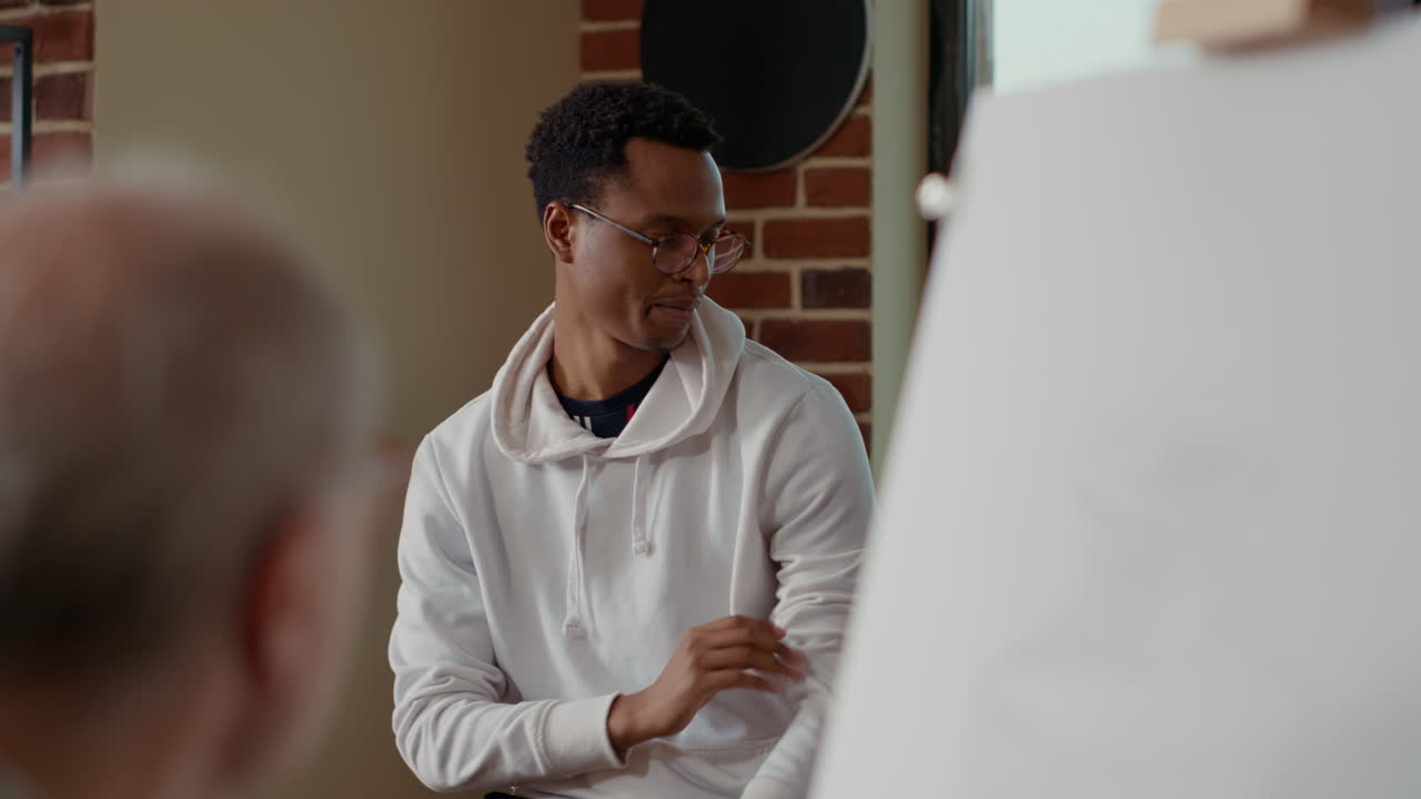 Artist teaching art student to draw sketch at creative workshop