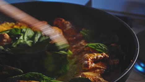 removing glass lid revealing juicy chicken breast with spinach in cheese and mayonnaise sauce, being cooked and stirred in a pan