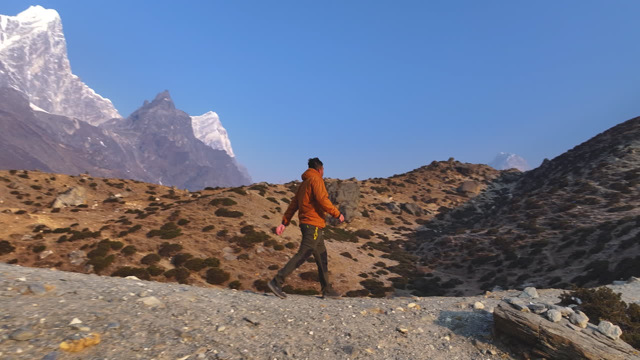 Drone shot of a tourist at a Buddhist stupa in Dingboche, Khumbu, Nepal. Mt. Cholatse rises in backdrop with sunrays over dry lands, creating scenic Himalayan expedition on the Everest Base Camp trek