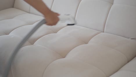 person cleaning a couch with a vacuum cleaner