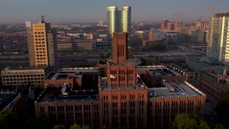 aerial pan showing sunrise illuminating the inktpot building with ufo resting on its facade flanked by modern skyscraper buildings