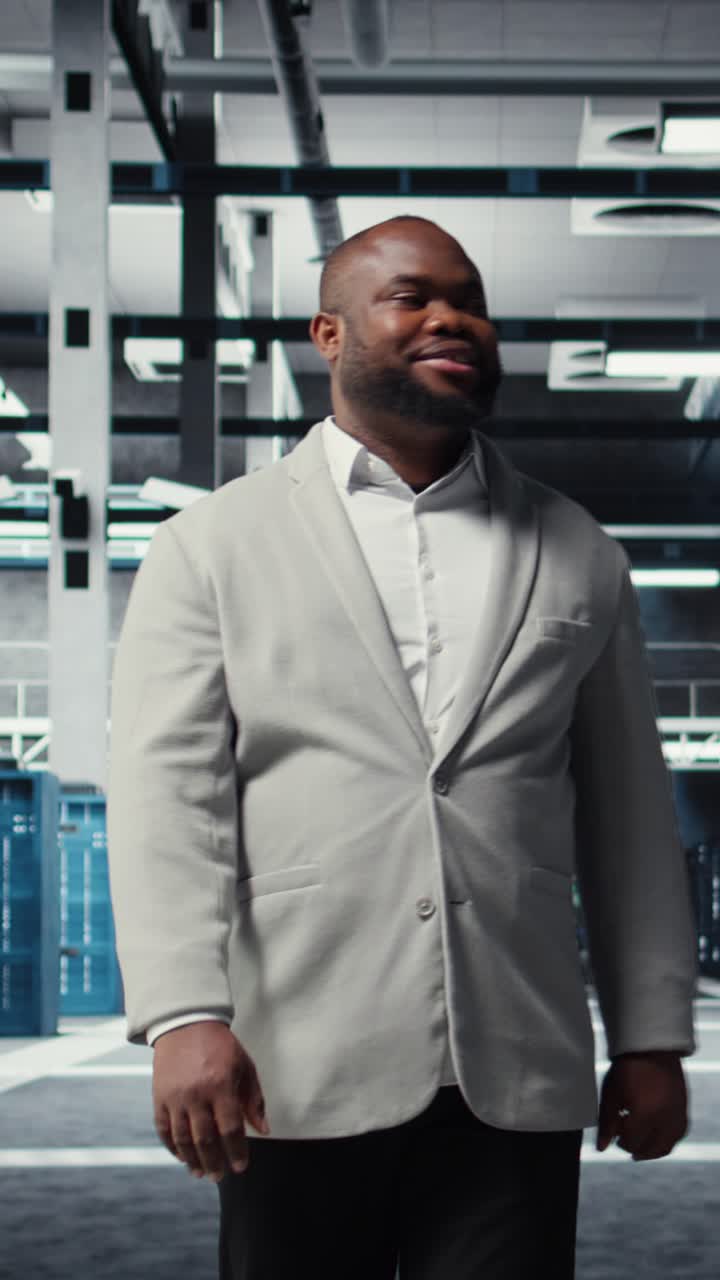 Vertical video Smiling engineer walking in data center, checking hardware for system stability