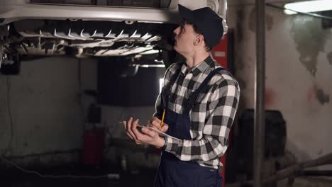 mechanic in auto repair service center using clipboard and paper to write down some results of car maintenance done