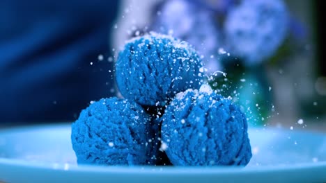 escena en cámara lenta de polvo rociado sobre cucharas de helado azul, encarnando el concepto de delicias dulces y postres en el arte culinario