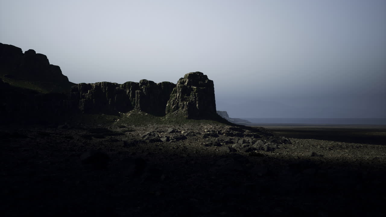 Dramatic rocky cliffs under dim light near a vast shoreline at dusk