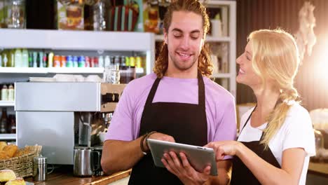 smiling waiter and waitress using digital tablet at counter