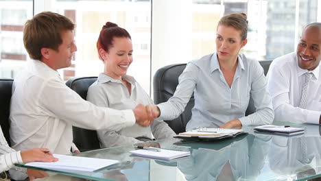 business group in an office with two shaking hands