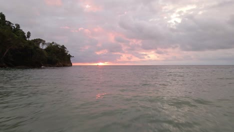 Vuelo-Rápido-De-Drones-Cerca-Del-Agua-Del-Océano-Hacia-Una-Bonita-Puesta-De-Sol-Naranja