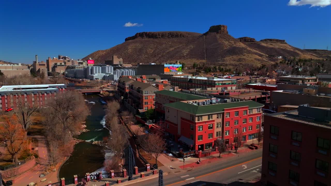 Historic downtown Golden Colorado aerial drone Clear Creek River North Table Mountain Coors Beer Factory Golden Gate Canyon winter snow sunny morning afternoon blue sky businesses buildings pan left