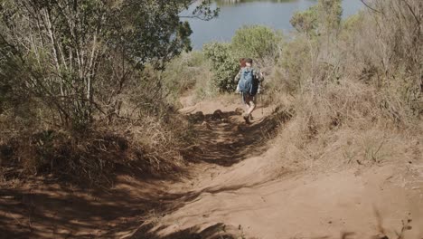 Happy-african-american-couple-wearing-backpacks-and-hiking-in-forest,-slow-motion