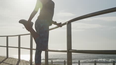 mujer mayor estirando sus piernas en un paseo marítimo