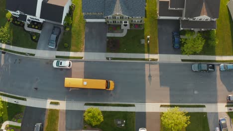 top down aerial of yellow school bus picking up students in housing development in usa