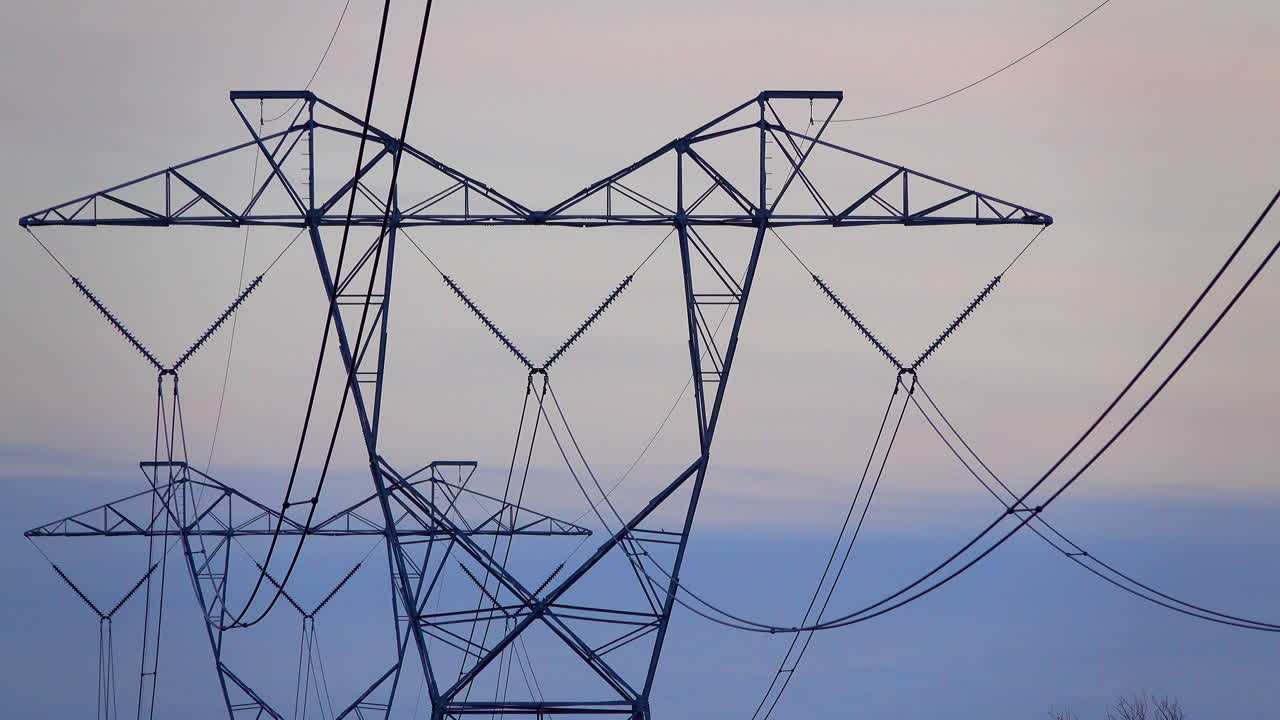 Close-up of electrical towers against an overcast sky